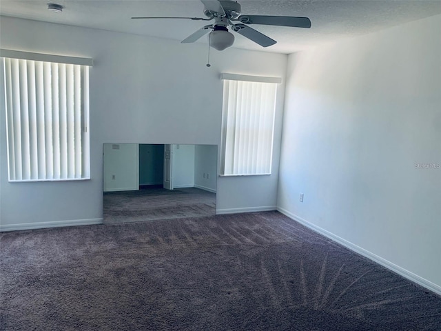 empty room with ceiling fan and dark carpet