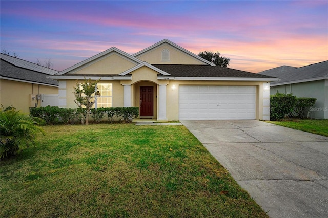 ranch-style home featuring a garage and a lawn