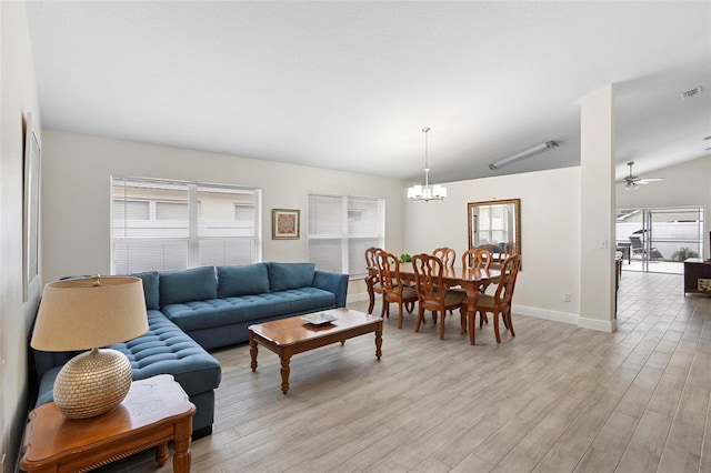 living room with light hardwood / wood-style floors, ceiling fan with notable chandelier, and a healthy amount of sunlight