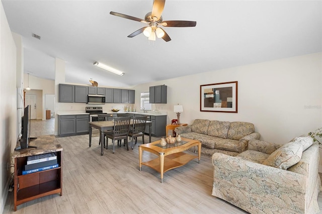 living room with ceiling fan, vaulted ceiling, and light hardwood / wood-style floors