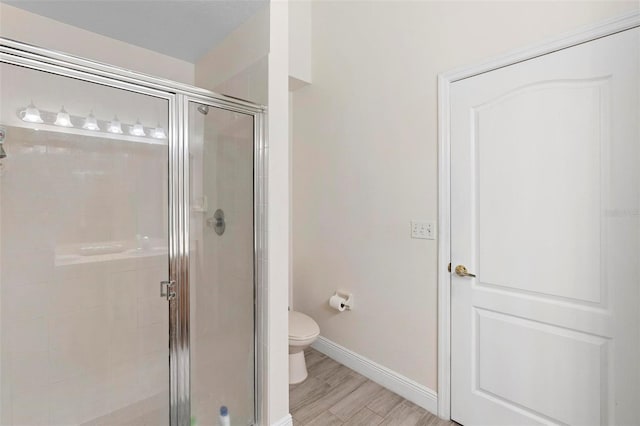 bathroom featuring an enclosed shower, toilet, and hardwood / wood-style flooring