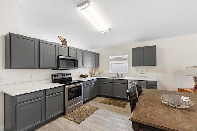 kitchen featuring stainless steel appliances, gray cabinetry, light wood-type flooring, a textured ceiling, and sink