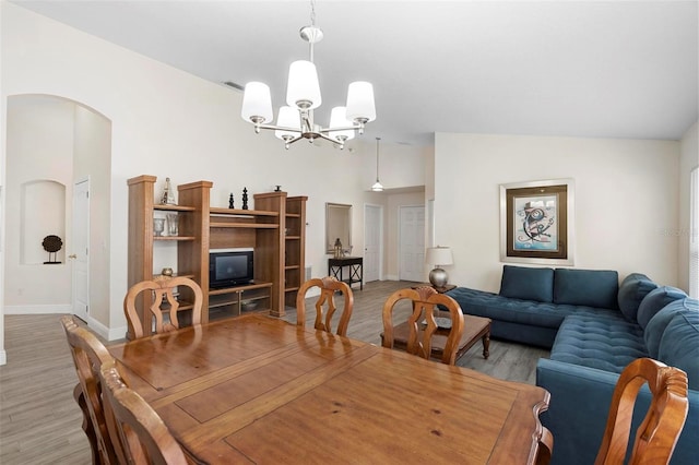 dining room featuring light hardwood / wood-style flooring, lofted ceiling, and a notable chandelier