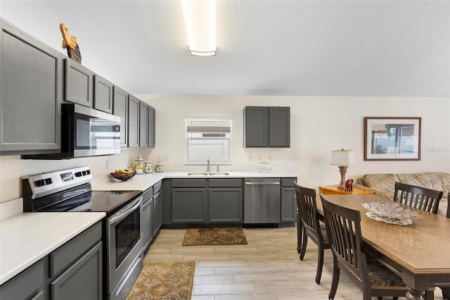 kitchen featuring light wood-type flooring, appliances with stainless steel finishes, sink, and gray cabinets