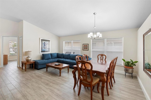 dining area with light hardwood / wood-style flooring, a notable chandelier, and vaulted ceiling