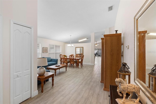 interior space with ceiling fan with notable chandelier and light hardwood / wood-style floors