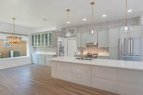 kitchen featuring hardwood / wood-style floors, stainless steel appliances, decorative backsplash, pendant lighting, and sink