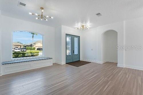 entryway with an inviting chandelier, light hardwood / wood-style floors, and french doors