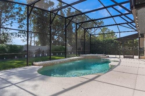 view of pool featuring glass enclosure and a patio