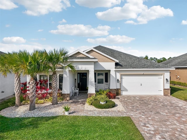 view of front of house featuring a garage, a front lawn, decorative driveway, and stucco siding