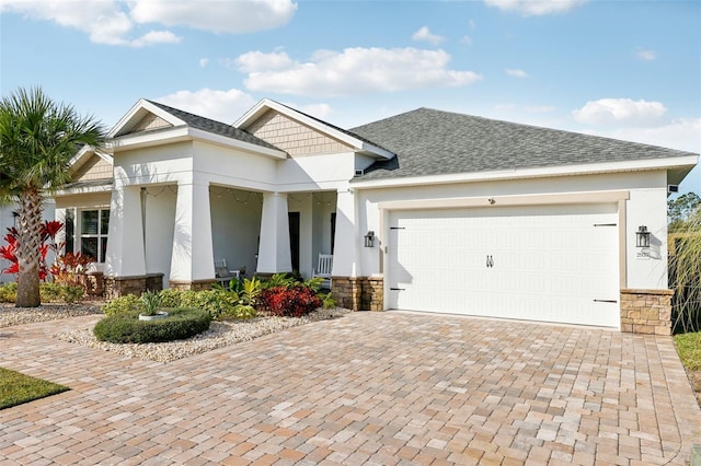 view of front of home featuring a garage, stone siding, decorative driveway, and stucco siding