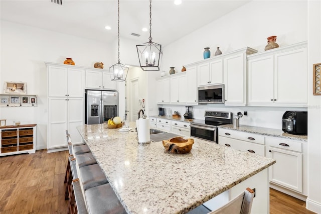 kitchen with stainless steel appliances, white cabinetry, and a large island