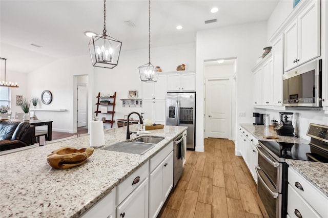 kitchen featuring white cabinets, light stone countertops, hanging light fixtures, and stainless steel appliances