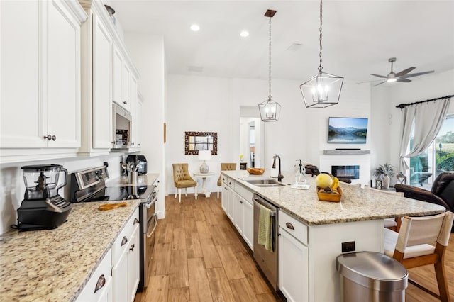 kitchen with sink, white cabinetry, appliances with stainless steel finishes, and a kitchen island with sink