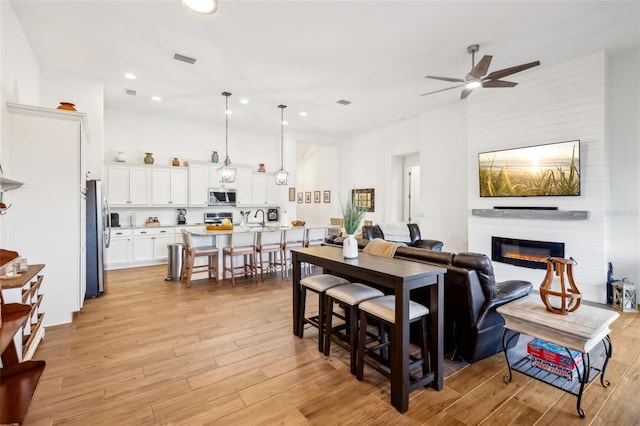 dining space with sink, ceiling fan, light hardwood / wood-style floors, and a fireplace