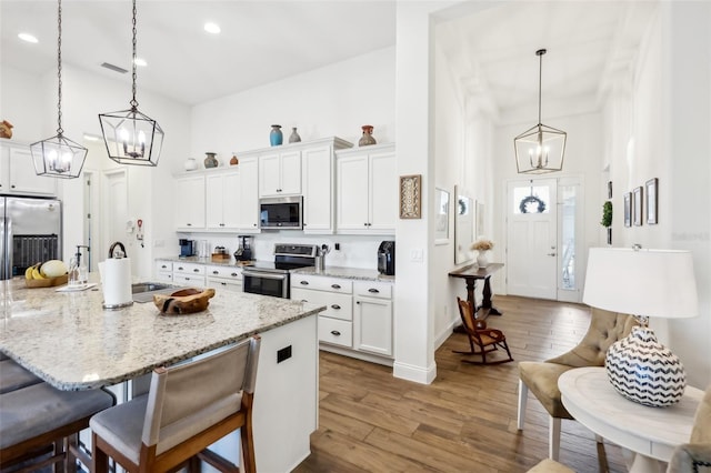 kitchen featuring sink, decorative light fixtures, dark wood-type flooring, white cabinetry, and stainless steel appliances