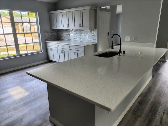 kitchen with light stone countertops, decorative backsplash, plenty of natural light, and sink