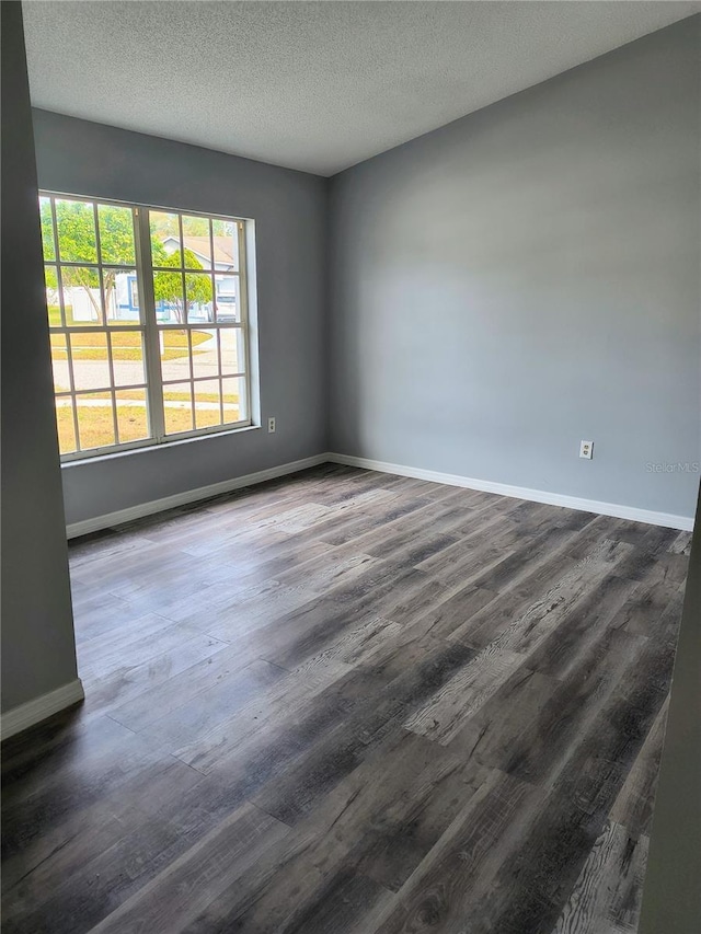 empty room with a textured ceiling and dark hardwood / wood-style flooring