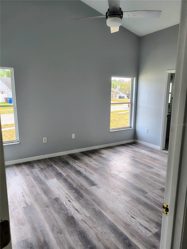 empty room featuring ceiling fan, high vaulted ceiling, and light hardwood / wood-style flooring