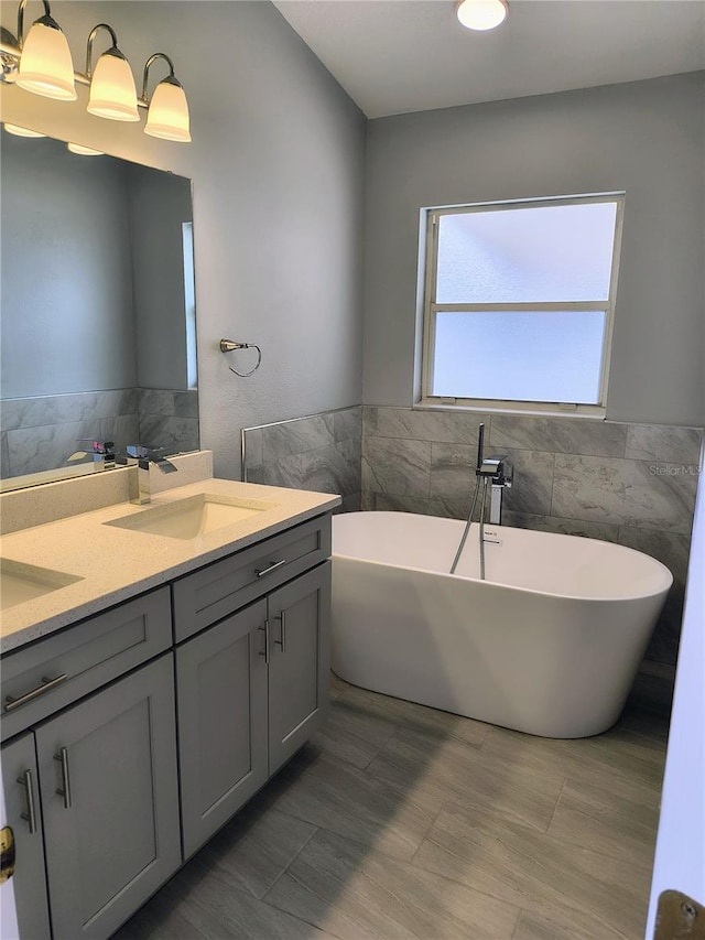 bathroom featuring tile walls, a tub to relax in, and vanity