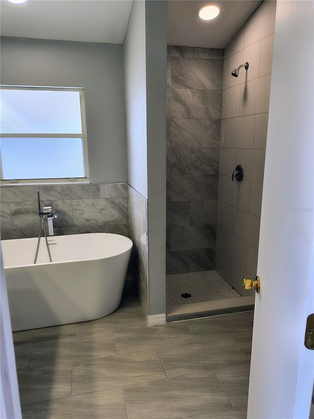 bathroom with plus walk in shower, tile patterned flooring, and tile walls