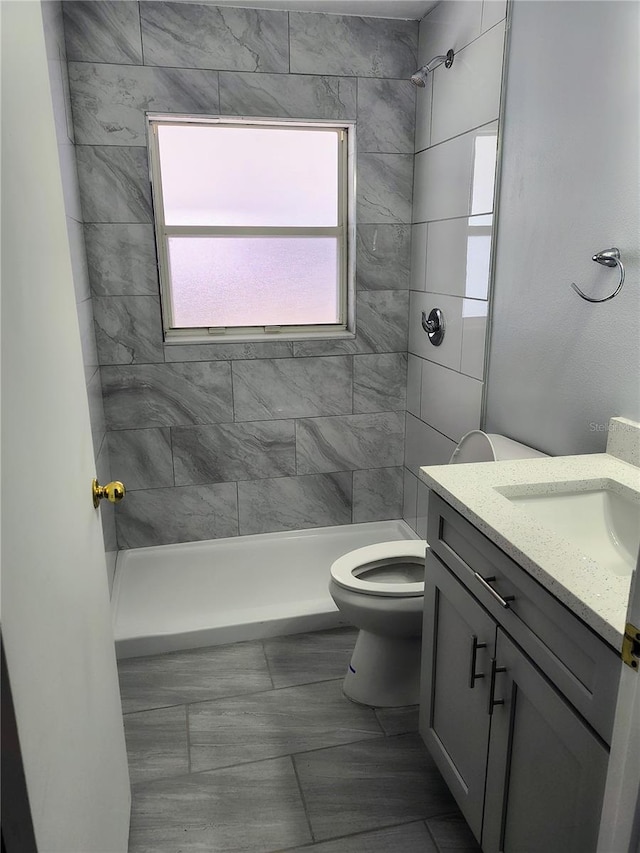 bathroom featuring toilet, vanity, and tiled shower