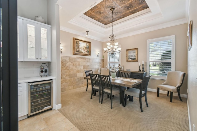 tiled dining room with ornamental molding, wine cooler, and a tray ceiling