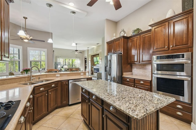 kitchen with sink, light tile patterned floors, appliances with stainless steel finishes, a center island, and tasteful backsplash