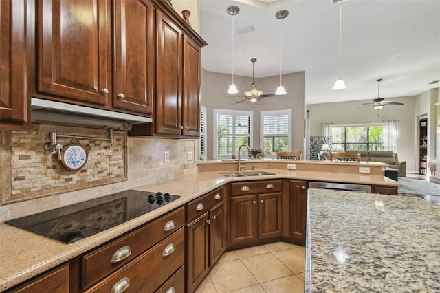 kitchen with light stone countertops, sink, black electric cooktop, and plenty of natural light