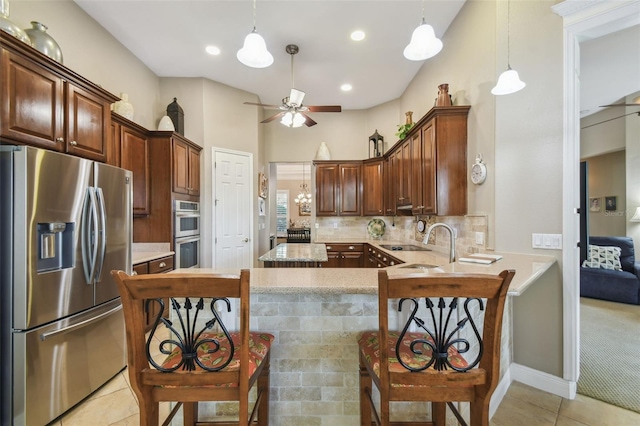 kitchen with sink, appliances with stainless steel finishes, light tile patterned flooring, decorative backsplash, and kitchen peninsula