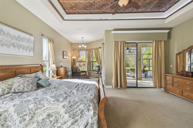 carpeted bedroom featuring access to exterior, multiple windows, and a notable chandelier