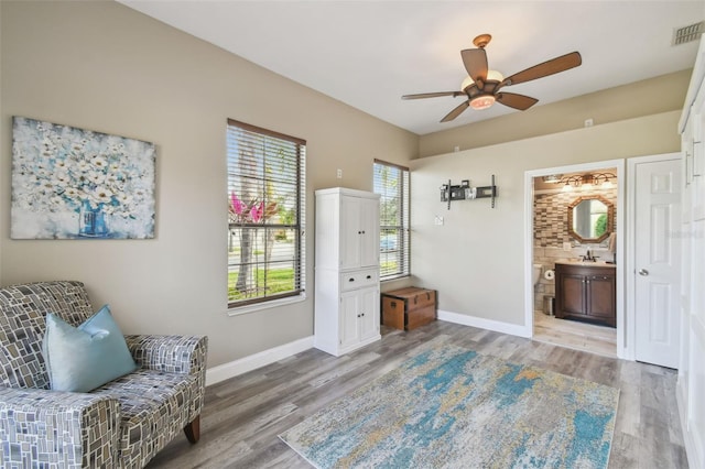 living area featuring ceiling fan, wood-type flooring, and sink