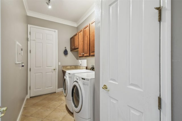 clothes washing area with crown molding, cabinets, washing machine and dryer, and light tile patterned floors