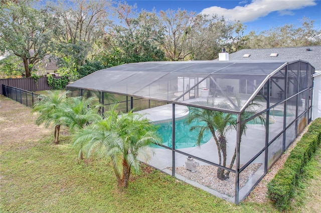 view of swimming pool with a yard and glass enclosure