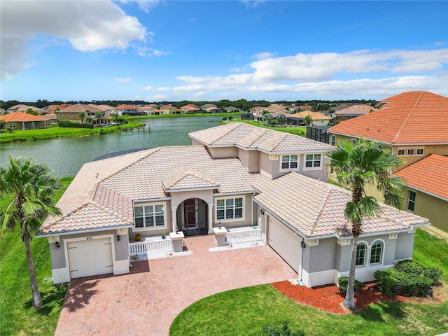 mediterranean / spanish-style home featuring a garage, a front yard, and a water view