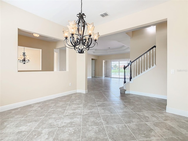 empty room featuring tile patterned flooring, a raised ceiling, and a notable chandelier