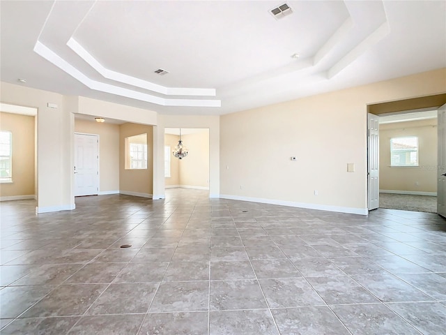 unfurnished living room featuring a raised ceiling, light tile patterned floors, and an inviting chandelier