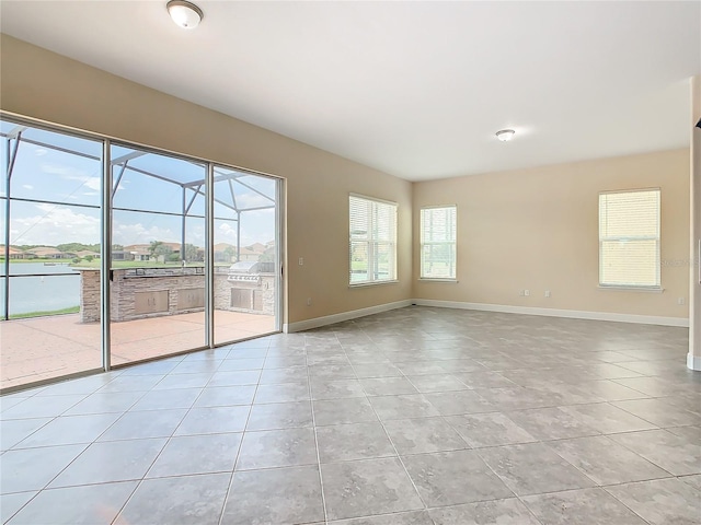 tiled empty room featuring a wealth of natural light and a water view