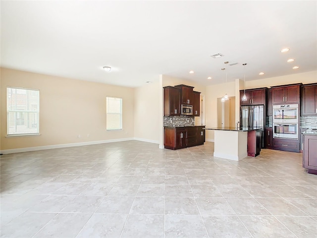 kitchen featuring light tile patterned floors, appliances with stainless steel finishes, a center island, and tasteful backsplash