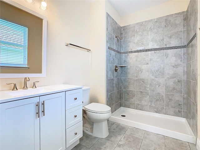 bathroom with toilet, vanity, tile patterned flooring, and a tile shower