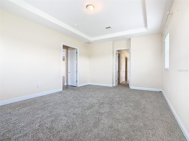 carpeted empty room with a raised ceiling