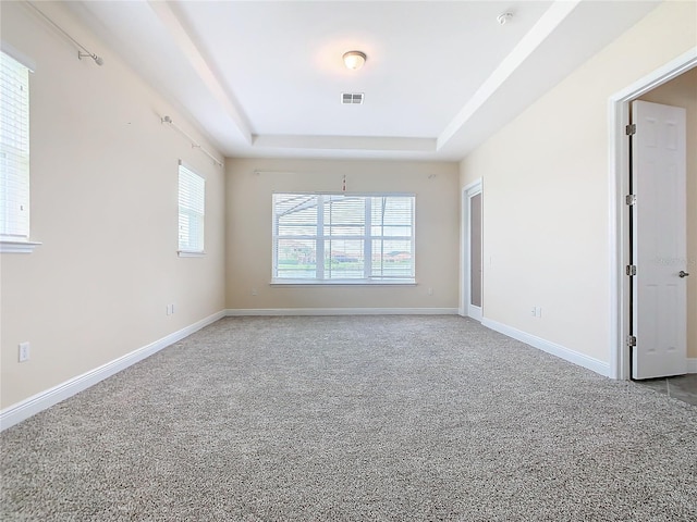 carpeted empty room with a tray ceiling