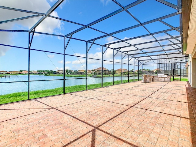 view of patio featuring a water view, an outdoor kitchen, and a lanai