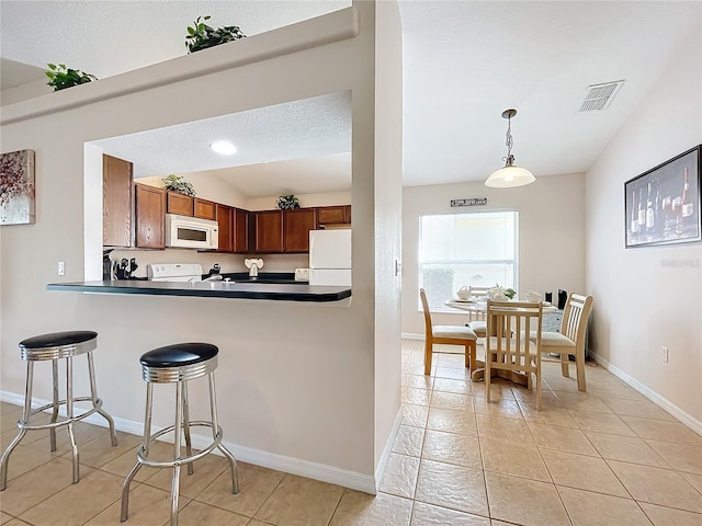 kitchen with white appliances, lofted ceiling, hanging light fixtures, kitchen peninsula, and light tile patterned flooring