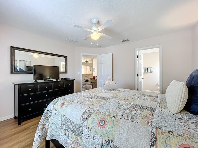 bedroom with ceiling fan, ensuite bathroom, and light wood-type flooring