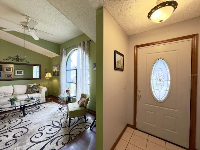 tiled foyer with lofted ceiling, ceiling fan, and a textured ceiling