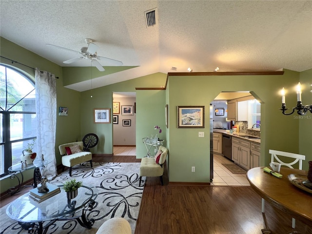 living room featuring a textured ceiling, lofted ceiling, light hardwood / wood-style floors, sink, and ceiling fan