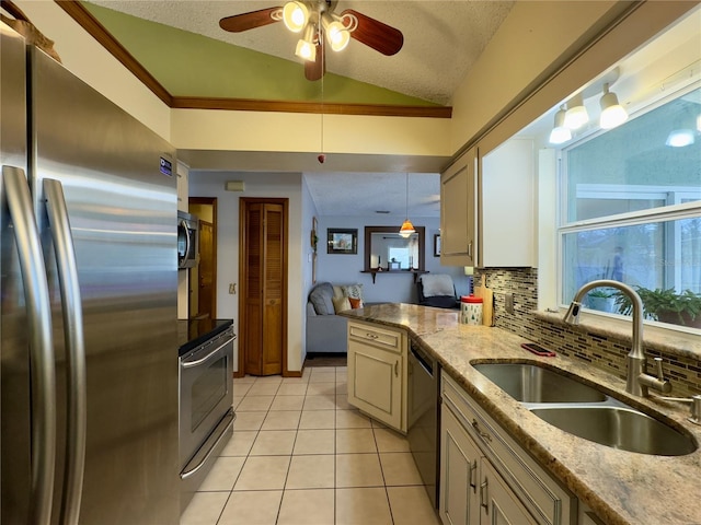 kitchen featuring decorative light fixtures, vaulted ceiling, sink, appliances with stainless steel finishes, and cream cabinets