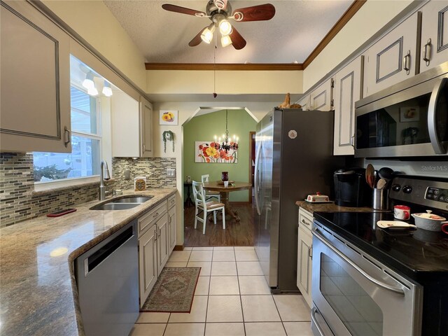 kitchen with stainless steel appliances, light tile patterned flooring, a textured ceiling, light stone counters, and sink