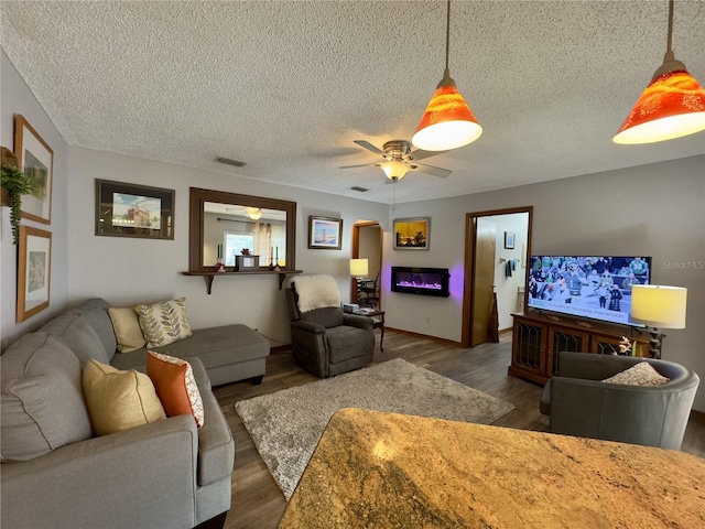 living room featuring ceiling fan, dark hardwood / wood-style floors, and a textured ceiling